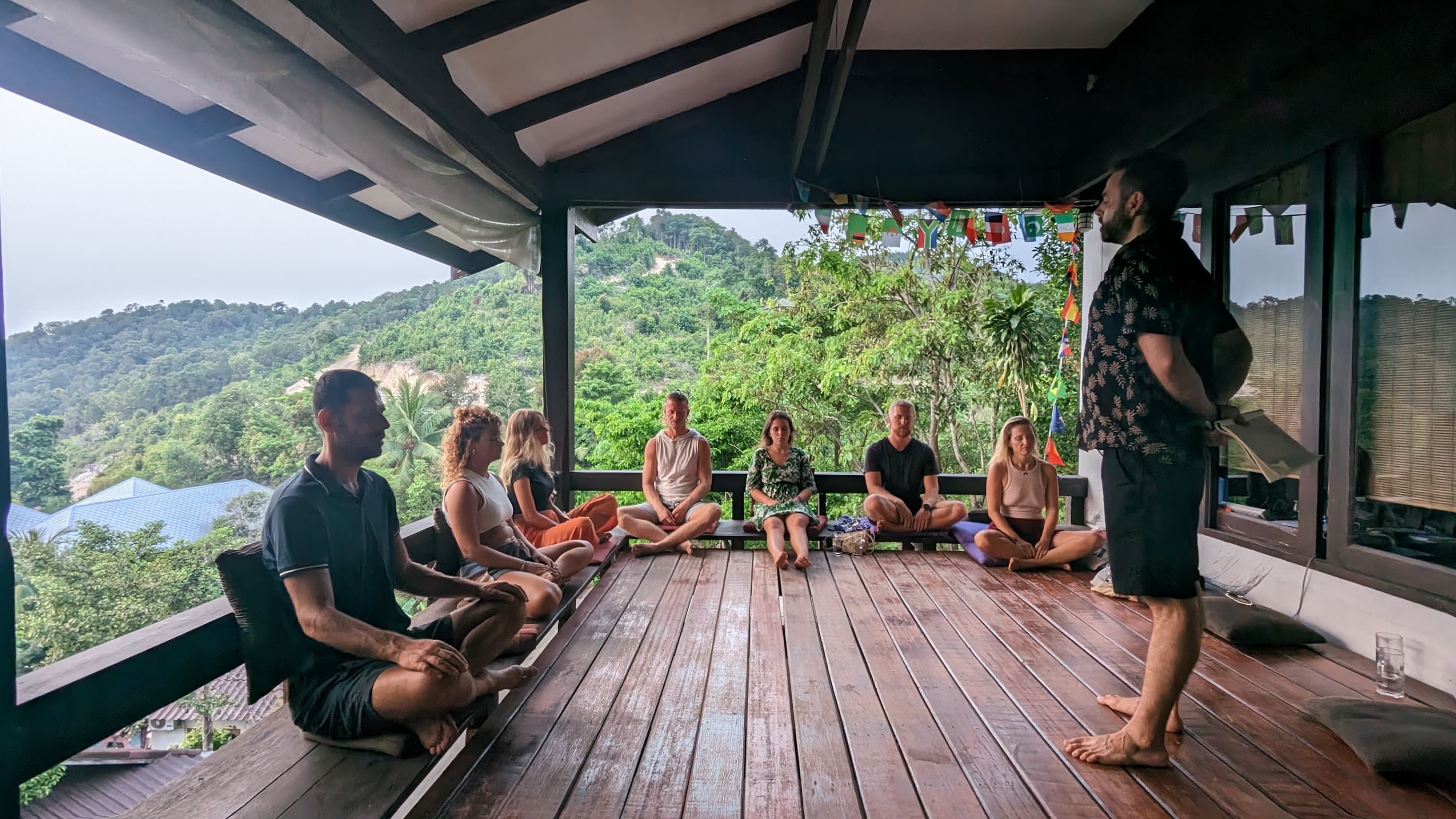 Barak standing on a wooden deck, guiding a live hypnosis session with a small group sitting upright around him.